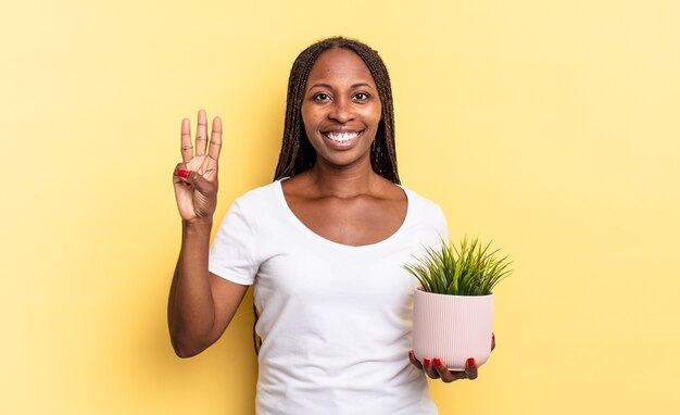 Sorridere e sembrare amichevole, mostrando il numero tre o il terzo con la mano in avanti, contando alla rovescia tenendo un vaso per piante