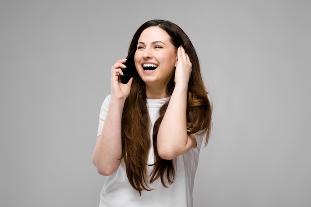 Sorridere emotivo felice plus size modello in piedi in studio guardando a porte chiuse parlando al telefono con un amico