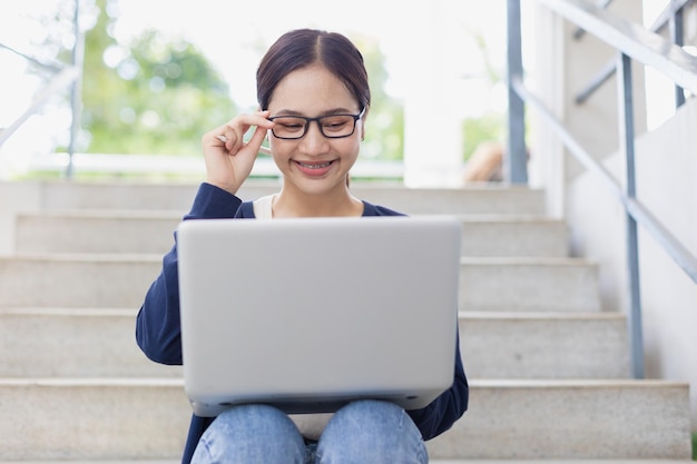 Sorridere felice della giovane ragazza teenager dell'università gode dell'uso del computer portatile per imparare l'istruzione nel campus scolastico