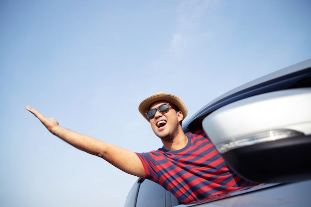 Sorridere felice elegante attraente bello del giovane uomo asiatico mentre si guida l'auto per viaggiare nel sole del mattino.