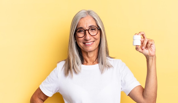 Sorridere felicemente con una mano sull'anca e un atteggiamento fiducioso, positivo, orgoglioso e amichevole e con in mano una bottiglia di pillole