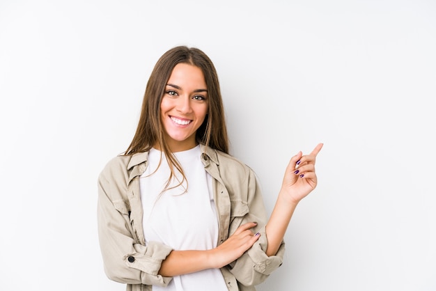 Sorridere isolato giovane donna caucasica che indica allegramente con l'indice via.