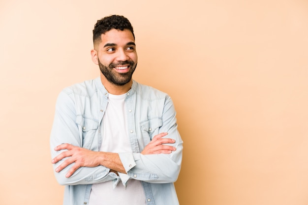 Sorridere isolato giovane uomo arabo della corsa mista sicuro con le armi attraversate.