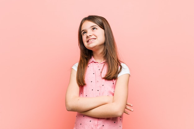 Sorridere sveglio della bambina sicuro con le braccia attraversate.