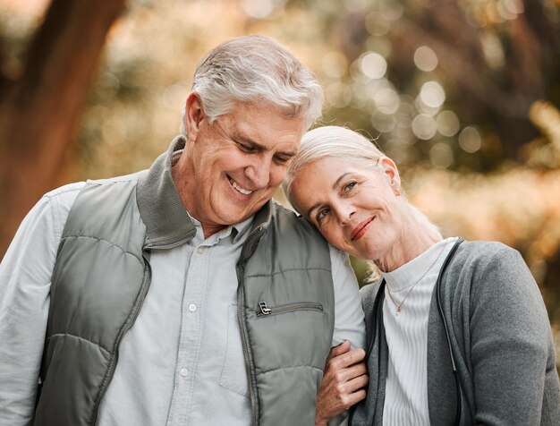 Sorridi amore e pace con una vecchia coppia nella natura per creare un legame felice e sostenere Rilassati la felicità e la pensione con un uomo e una donna anziani che camminano nel parco di campagna per vacanze e impegno