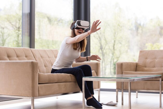 Sorridi donna felice che fa esperienza con gli occhiali VR-headset della realtà virtuale a casa