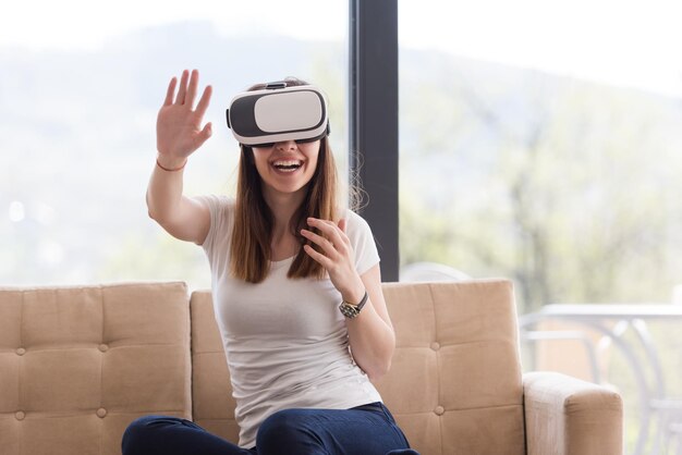 Sorridi donna felice che fa esperienza con gli occhiali VR-headset della realtà virtuale a casa