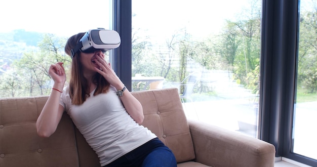 Sorridi donna felice che fa esperienza con gli occhiali VR-headset della realtà virtuale a casa