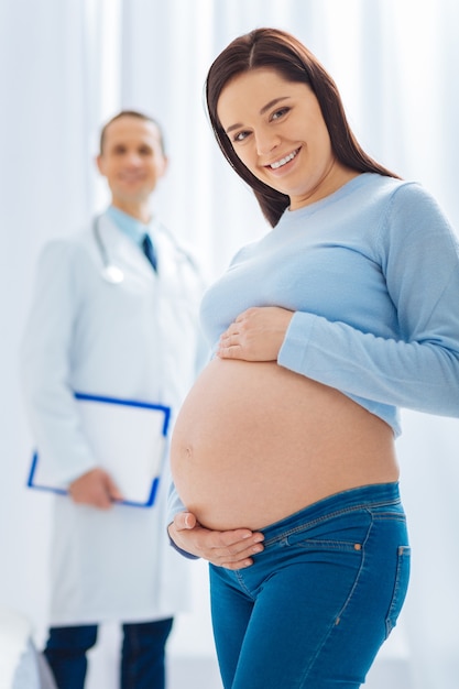 Sorridi e basta. Persona di sesso femminile che aspetta un bambino e mantiene il sorriso sul suo viso mentre guarda avanti