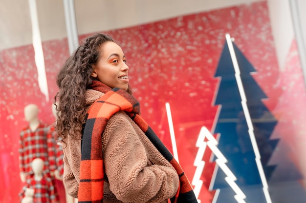 Sorridi felice donna che cammina all'aperto in una città di celebrazione prima di Natale in cerca di regali