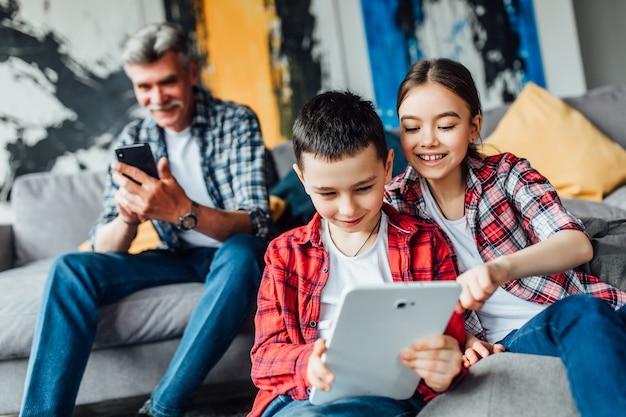 Sorridi fratello e sorella che giocano sul laptop con il nonno.