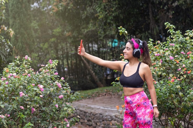 Sorridi per la fotocamera La donna latina si fa un selfie dopo una sessione di allenamento all'aperto in giardino