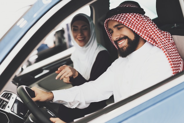 Sorrisi arabi allegri dell'uomo d'affari alla nuova automobile.