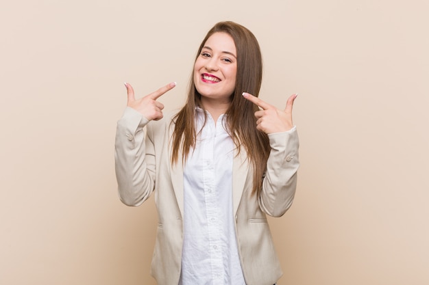 Sorrisi di giovane donna d'affari, puntando le dita in bocca.