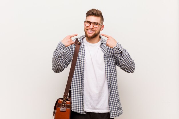 Sorrisi di giovane uomo d'affari moderno, puntando le dita alla bocca.