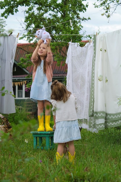 Sorrisi illuminati dal sole che ridono sotto il sole un bambino vivace fa del bucato in giardino un'avventura mirata