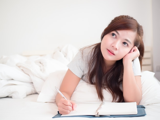 Sorriso abbastanza asiatico allegro della donna e felice sul letto in camera da letto