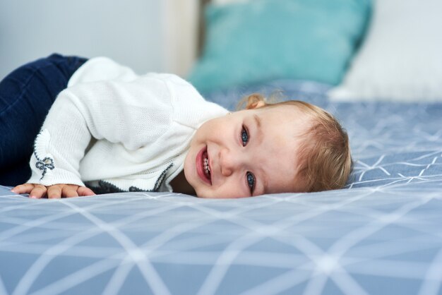 Sorriso amichevole della neonata che si trova sul letto