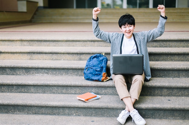 Sorriso asiatico dello studente con fiducia e sulla mano felicemente.