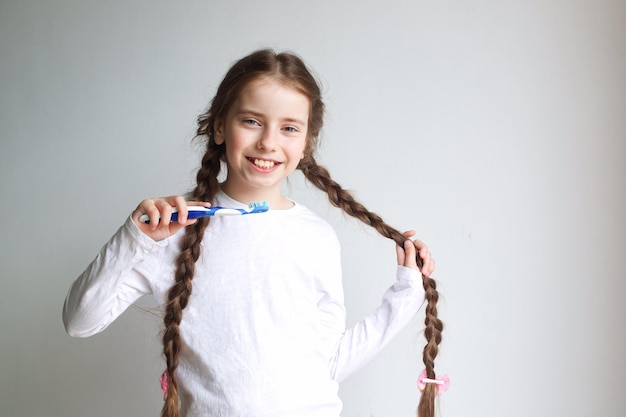 Sorriso bambina lavarsi i denti su uno sfondo chiaro