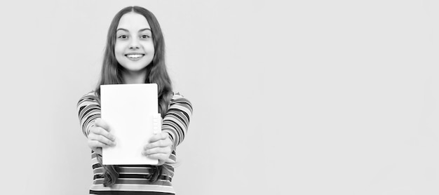 Sorriso bambino felice che mostra il libro di scuola per lo spazio di copia conoscenza di sfondo giallo Banner di studentessa della scuola Ritratto di studentessa con spazio di copia