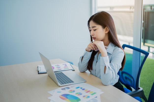 Sorriso della donna freelance di affari asiatici digitando sulla tastiera e lavorando al computer portatile sul tavolo di legno a casa Donna imprenditrice che lavora per la sua attività in ufficio Lavoro aziendale in ufficio a casa