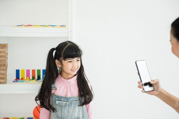 Sorriso della figlia di Adorbale guarda il telefono della madre a casa.