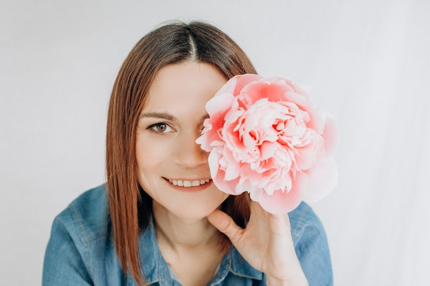 Sorriso della ragazza della mano del fiore della peonia vicino