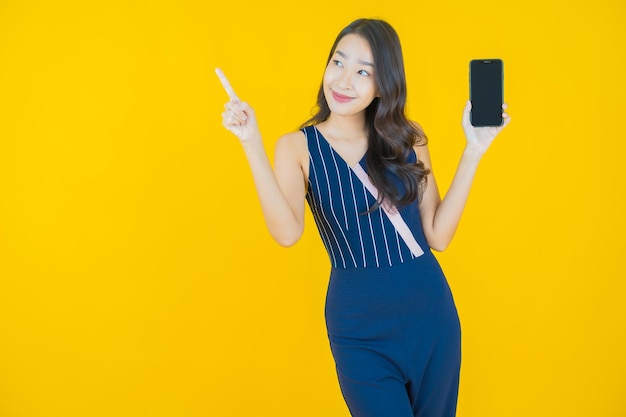 Sorriso di bella giovane donna asiatica del ritratto con il telefono cellulare astuto acceso