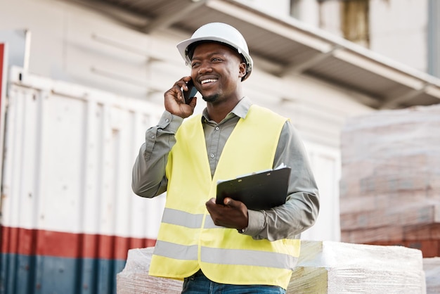 Sorriso di telefonata e ingegnere uomo di colore in cantiere che parla o in discussione per contattare la conversazione mobile Comunicazione del settore e architettura di pianificazione dei lavoratori come costruttore