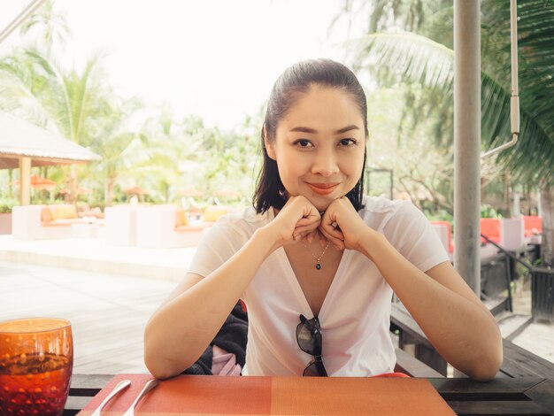Sorriso donna asiatica sedersi nel ristorante resort tropicale