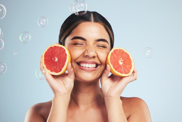 Sorriso donna e cura della pelle pompelmo in studio per cosmetici naturali o benessere su sfondo grigio Bellezza felice e viso modello con agrumi facciali o vitamina C collagene ed estetica a bolle