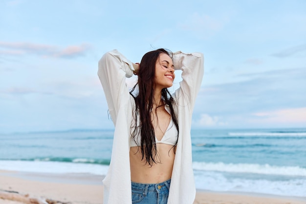 Sorriso e felicità della donna che camminano sulla spiaggia e si divertono a sorridere con i denti con gli occhi chiusi davanti all'oceano vacanza viaggio estivo tramonto sulla spiaggia dell'isola di Bali