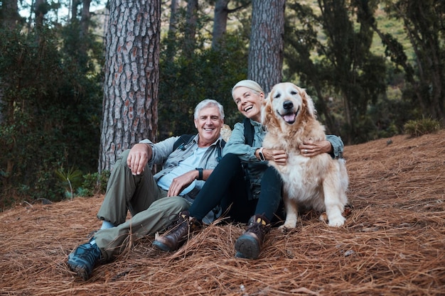 Sorriso escursionismo e vecchia coppia con cane seduto sul suolo della foresta in Australia durante l'avventura per le vacanze di pensionamento Viaggia uomo anziano e donna rilassati insieme durante una passeggiata nella natura con amore Labrador e salute