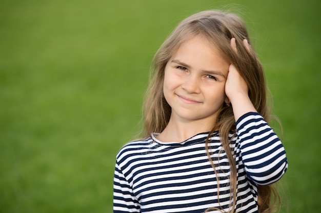 Sorriso felice del ragazzino che corre le dita attraverso lo spazio della copia di cura dei capelli del paesaggio naturale di estate dei capelli biondi lunghi