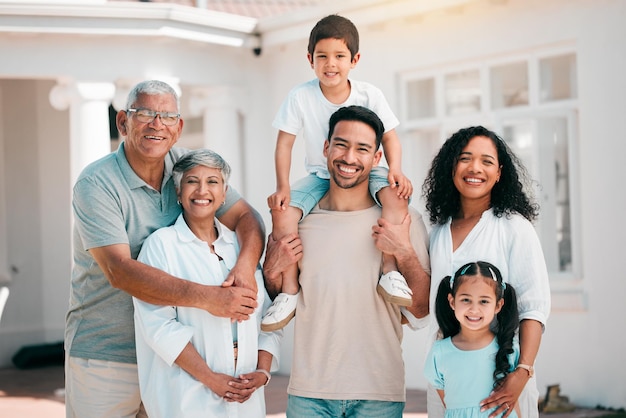 Sorriso felice e ritratto di una grande famiglia all'aperto insieme nel cortile della loro casa moderna Felicità eccitata e bambini che legano con i loro nonni e genitori in un giardino vicino a casa loro