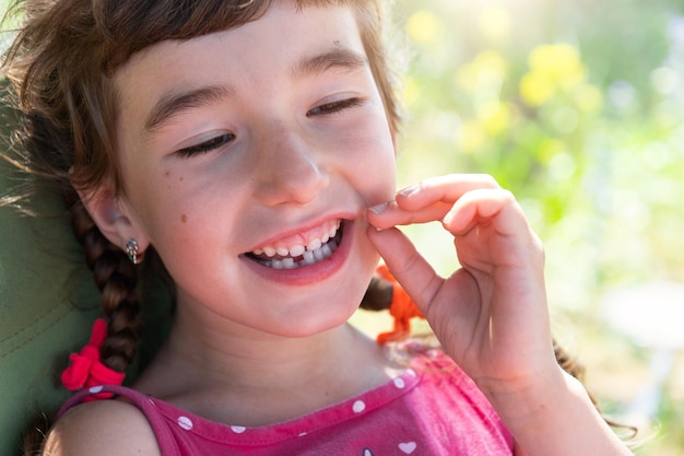 Sorriso felice senza denti di una ragazza con un primo piano del dente di latte inferiore caduto Cambiare i denti ai molari durante l'infanzia