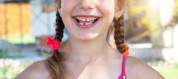 Sorriso felice senza denti di una ragazza con un primo piano del dente di latte inferiore caduto Cambiare i denti ai molari durante l'infanzia