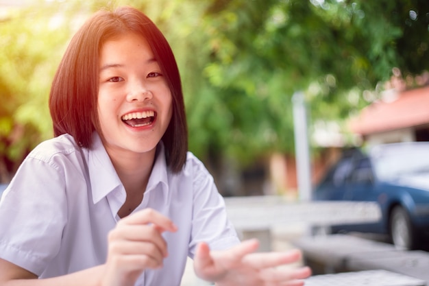 Sorriso felice studentessa asiatica ragazza adolescente giovane carina seduta all'aperto con fotocamera con spazio per le copie