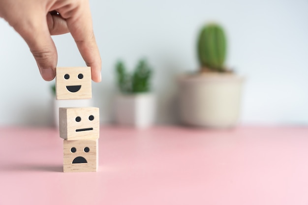 Sorriso icona volto e carrello sul cubo di legno. Persona o persone ottimiste che si sentono dentro e valutano il servizio quando fanno acquisti, concetto di soddisfazione.