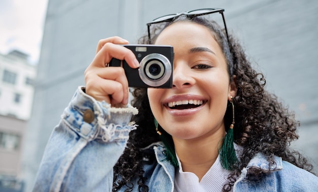 Sorriso per la fotocamera Inquadratura di una giovane donna che tiene la sua fotocamera mentre è in piedi fuori