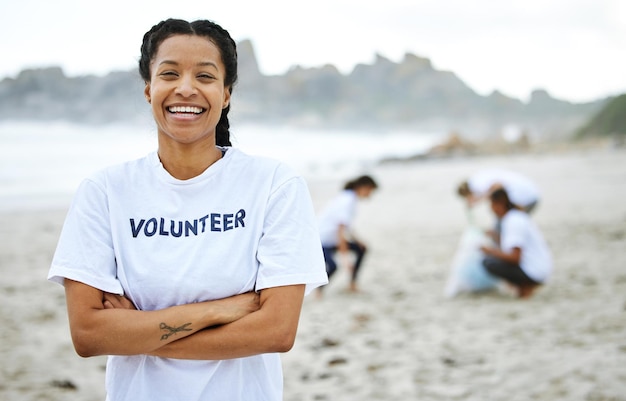 Sorriso ritratto e donna volontaria in spiaggia per la pulizia, riciclaggio e sostenibilità Giornata della Terra ridente e orgogliosa donna con le braccia incrociate per beneficenza di servizio alla comunità e cambiamento climatico