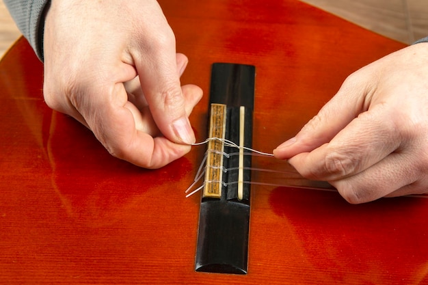 Sostituzione e inserimento di corde di nylon in una chitarra classica. lezione per un musicista