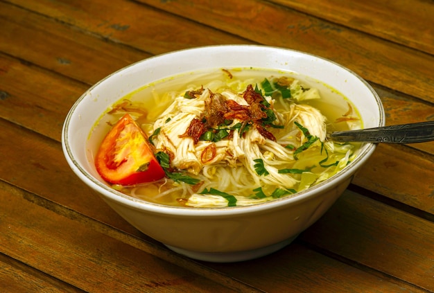 Soto Ayam, una zuppa di pollo tradizionale indonesiana su un tavolo di legno, focus selezionato