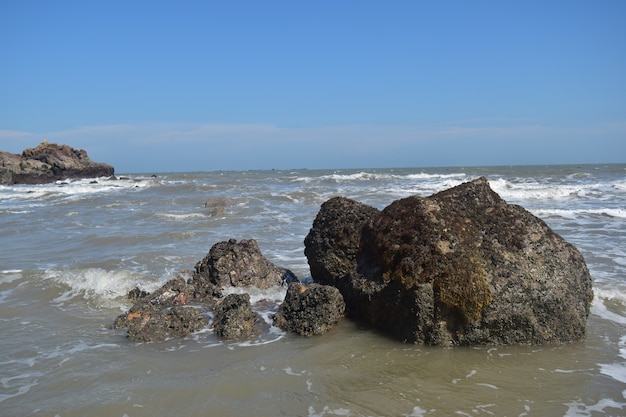 Sotto il cielo azzurro, le onde battono gli scogli sulla spiaggia