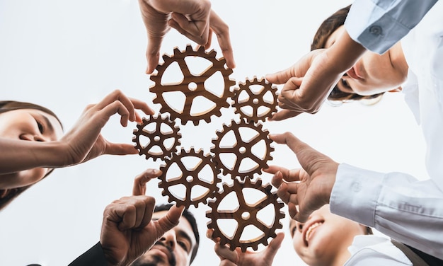 Sotto la vista impiegato che tiene la ruota dentata come unità e lavoro di squadra nel concetto di posto di lavoro aziendale Diversi colleghi uomini d'affari come simbolo del lavoro di squadra del sistema visionario per il successo aziendale Concord