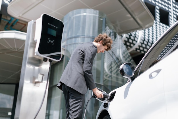 Sotto vista primo piano progressivo vestito nero uomo d'affari ricaricare la batteria dell'auto EV