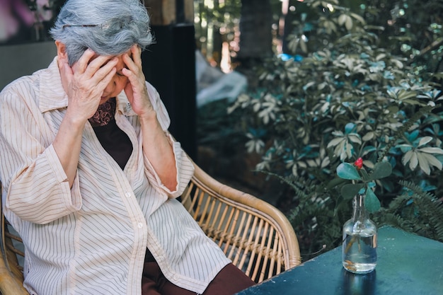 Sottolineato depresso affaticato triste sconvolto asiatico vecchio asiatico anziano anziano anziano donna seduta in giardino.