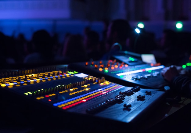 Soundman che lavora al mixer in una sala da concerto. Mani sui cursori.