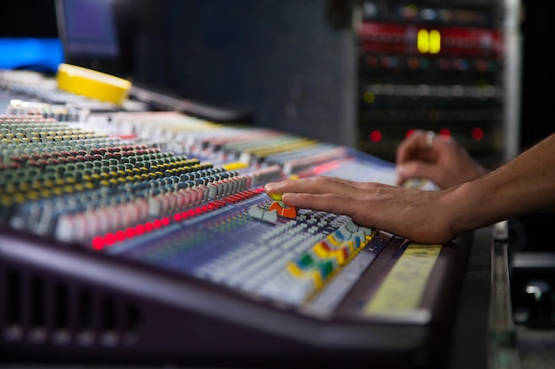 Soundman che lavora alla console di mixaggio. Mani sui cursori.